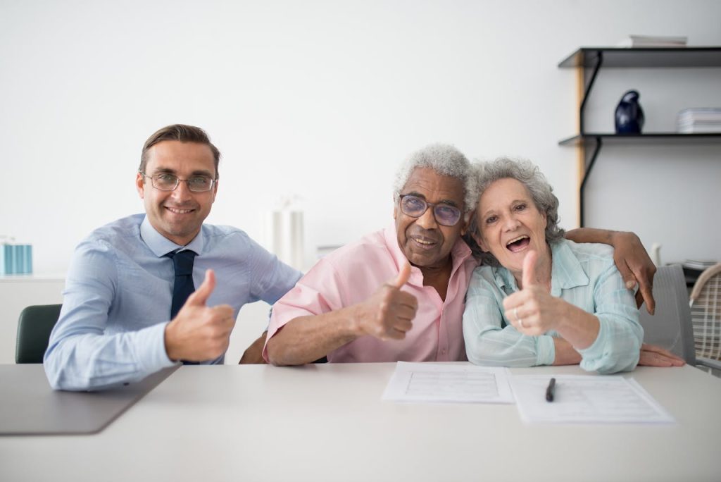 pexels-photo-8441870 Elderly couple with consultant giving thumbs up in an office setting, showcasing positive interaction.